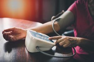 bicipite del braccio superiore della donna anziana in polsino. anziana signora in pensione che misura manualmente la pressione sanguigna, utilizzando il tonometro digitale a casa. assistenza sanitaria, concetto di trattamento delle malattie. foto