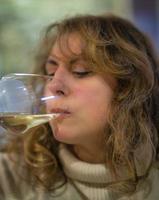 donna matura che degusta un bicchiere di vino bianco, all'interno di una cantina di oltrepo pavese, lombardia, nord italia. questa zona è famosa nel mondo per i suoi pregiati vini rossi e bianchi frizzanti.