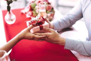 la coppia dell'uomo tiene in mano un regalo romantico rosso regalo regalalo alla ragazza. foto