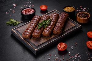 kebab alla griglia con spezie ed erbe aromatiche su fondo di cemento scuro foto