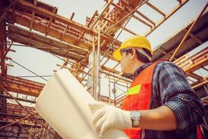 ingegnere lavoratore uomo che tiene progetto di controllo e pianificazione del progetto in cantiere foto