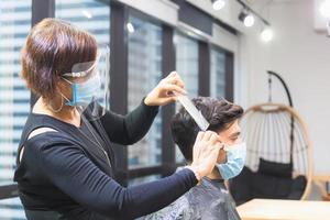 giovane uomo che si fa tagliare i capelli dal parrucchiere, barbiere con forbici e pettine, nuovo concetto normale foto