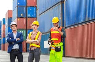 squadra di ingegnere e caposquadra in elmetto protettivo e giubbotto di sicurezza al container foto