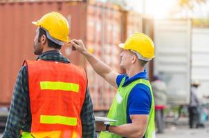 ingegnere e squadra di lavoratori che controllano la scatola dei contenitori dal carico con sfondo sfocato, concetto di lavoro di squadra foto