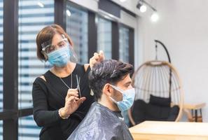 giovane uomo che si fa tagliare i capelli dal parrucchiere, barbiere con forbici e pettine, nuovo concetto normale foto