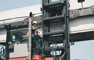 lavoratore uomo in elmetto protettivo e giubbotto di sicurezza che tiene il laptop in piedi su impilatori di container controllano il caricamento della scatola dei container dal carico foto