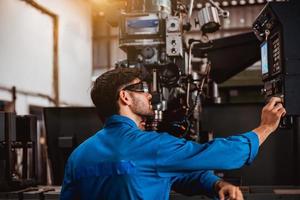 ingegneria industriale che indossa un controllo uniforme di sicurezza che opera la rettificatrice del tornio che lavora nella fabbrica industriale. foto