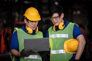 ingegneria industriale che indossa un controllo uniforme di sicurezza che opera una rettificatrice per tornio controllata da computer che lavora in una fabbrica industriale. foto