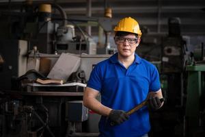 ingegneria industriale che indossa un controllo uniforme di sicurezza che opera una rettificatrice per tornio controllata da computer che lavora in una fabbrica industriale. foto