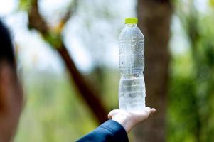 concetto creativo dell'acqua potabile della bottiglia d'acqua e della mano con lo spazio della copia foto