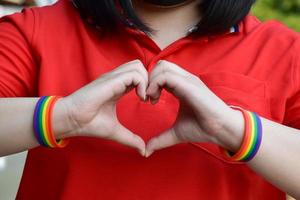 braccialetti arcobaleno nei polsi di una coppia di ragazzi asiatici con sfondo sfocato, concetto per la celebrazione della comunità lgbt nel mese dell'orgoglio o nel giugno in tutto il mondo foto