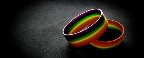 braccialetti arcobaleno di gomma su sfondo nero, luce al neon modificata, simbolo lgbt, concetto per le celebrazioni delle comunità lgbtq nel mese dell'orgoglio in tutto il mondo. foto