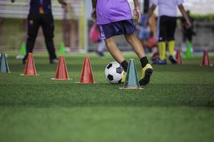 bambini che giocano a controllare le tattiche del pallone da calcio sul campo in erba con per l'allenamento foto