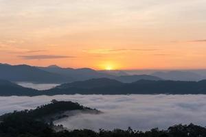 l'alba sulle grandi montagne e la nebbia sulla foresta in inverno foto