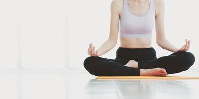 adattare la giovane donna che fa esercizi di yoga seduto mudra della mano e medita nel soggiorno di casa, foto