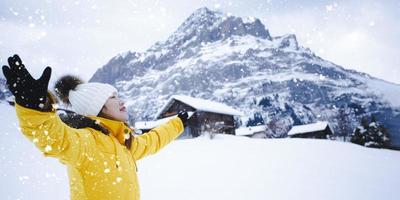 grindelwald svizzera cima d'europa, donna asiatica che indossa un cappotto giallo. usa lo smartphone scatta una foto montagna di neve nella sua vacanza in montagna, viaggio inverno nevoso sul monte a grindelwald.