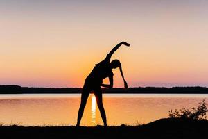 ragazza al tramonto in riva al lago foto