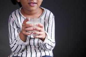 bambina che beve latte mentre è seduta foto