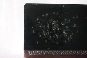 schermo del laptop rotto sul tavolo da vicino foto