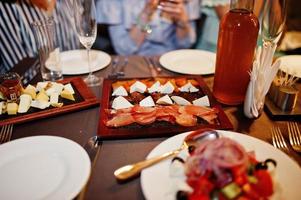 foto ravvicinata di deliziose fette di carne, formaggio, insalata e bevanda alcolica sul tavolo all'addio al nubilato.