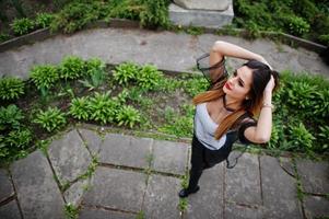 sopra la vista della donna alla moda guarda una camicia bianca, abiti neri trasparenti, pantaloni di pelle, in posa per strada. concetto di ragazza di moda. foto