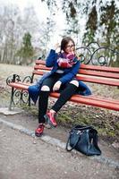 giovane ragazza che fuma sigaretta all'aperto seduto su una panchina. concetto di dipendenza da nicotina da parte degli adolescenti. foto