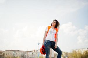 ingegnere costruttore donna in gilet uniforme e casco protettivo arancione contro i nuovi edifici. foto