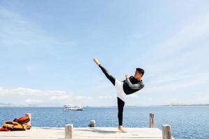 l'uomo asiatico del combattente con il calcio del taekwondo posa con il mare sullo sfondo foto