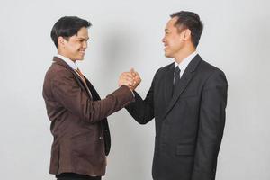 due uomini d'affari asiatici in giacca e cravatta che si guardano facendo una stretta di mano di squadra per il loro successo foto