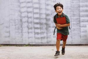 ragazzo asiatico entusiasta dello studente che corre e va a scuola foto