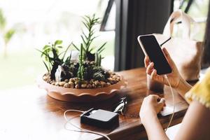 vista posteriore della donna utilizza il dispositivo smartphone e carica il cellulare con power bank foto