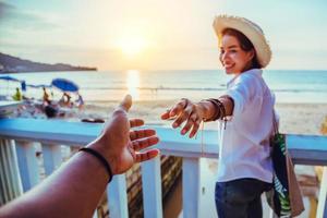 gli amanti asiatici felici e sorridi tenendosi per mano. viaggio in spiaggia per le vacanze estive. foto