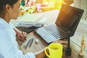 donne sedute a lavorare sul tavolo di legno che lavorano con un taccuino e bevono caffè a casa. in vacanza foto