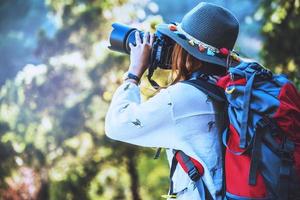 fotografo donne asiatiche viaggiano nella natura. viaggiare rilassati. studio della natura. al parco pubblico in estate. in Thailandia foto