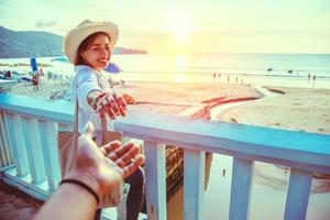 gli amanti asiatici felici e sorridi tenendosi per mano. viaggio in spiaggia per le vacanze estive. foto