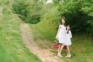 due sorelle vestite di bianco si divertono insieme durante l'estate. le ragazze tengono i fiori. foto