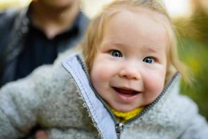 papà caucasico sorridente felice con la neonata adorabile sveglia. famiglia in autunno parco autunnale all'aperto con alberi di foglie di arancio giallo. foto