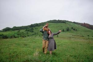 mamma, papà e figlia. i genitori tengono il bambino per mano e vanno verso la telecamera. foto