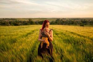 una madre tiene teneramente in braccio il figlio di tre mesi in un campo di grano. foto