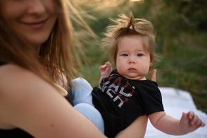 giovane madre che abbraccia il bambino carino all'aperto foto