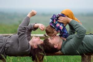 mamma, papà e figlia. i genitori tengono il bambino per mano e vanno verso la telecamera. foto