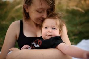 giovane madre che abbraccia il bambino carino all'aperto foto