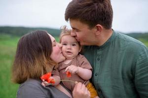 mamma, papà e figlia. i genitori tengono il bambino per mano e vanno verso la telecamera. foto