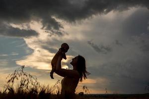 una madre tiene teneramente in braccio il figlio di tre mesi in un campo di grano. foto