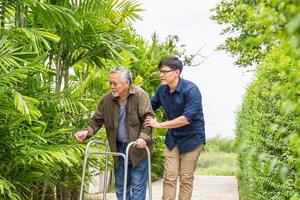 padre asiatico anziano e figlio di mezza età camminano nel parco, uomo anziano anziano con figlio che cammina all'aperto in giardino, concetti di famiglia asiatica di felicità foto