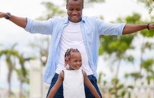 padre felice che gioca con la figlia, ragazza afroamericana allegra che gioca con suo padre foto