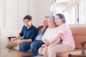 figlia senior madre padre e figlio di mezza età seduti sul divano, famiglia asiatica allegra che guarda la televisione in soggiorno, concetti di famiglia di felicità foto