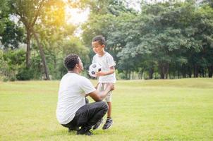 allegro padre e figlio afroamericani che giocano con il calcio nel parco, concetti di famiglia di felicità foto