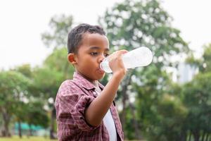 acqua potabile del ragazzo afroamericano dopo aver giocato al parco foto