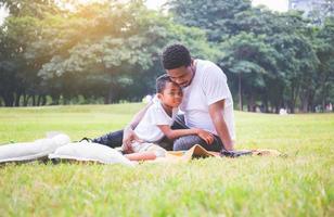 padre e figlio afroamericani che fanno un picnic nel parco, concetti di famiglia di felicità foto